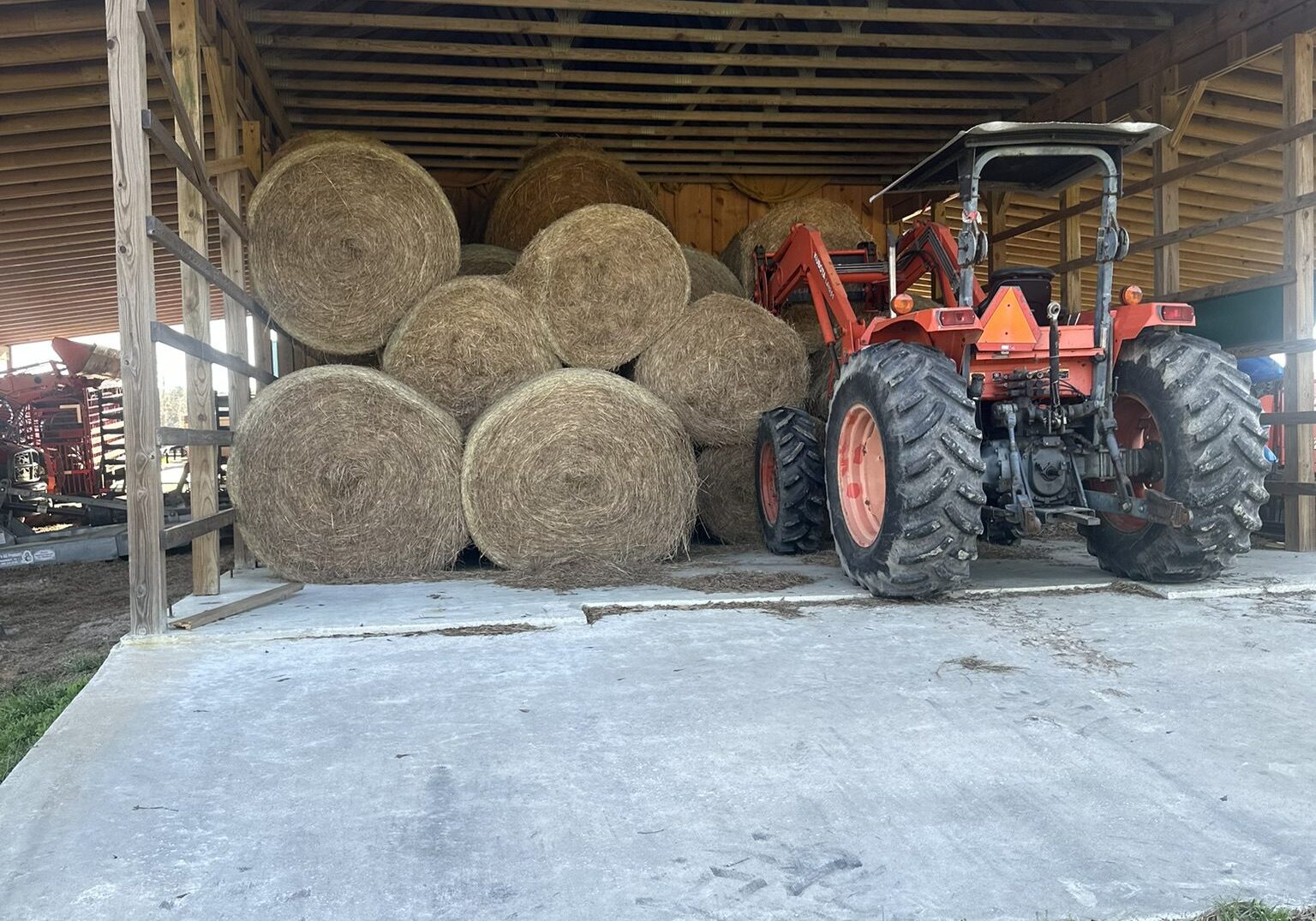 67f58c73575c7_Image20250408135042 A tractor parked in front of hay bales.
