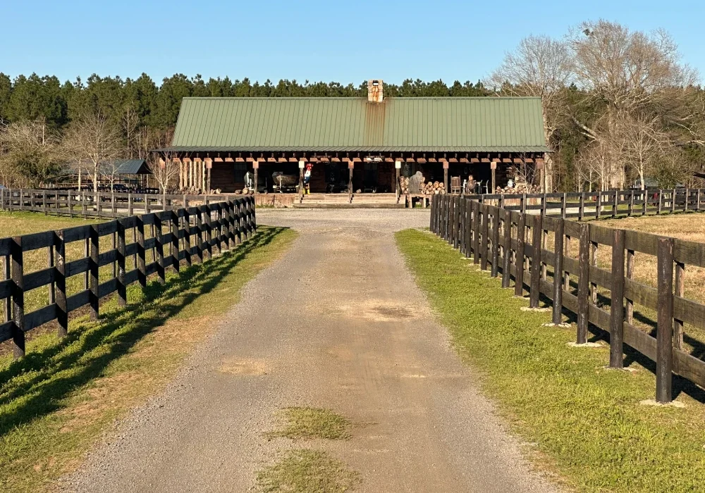 67f58d3838a6b_7F365D6B-0E57-449C-A3E4-BBF2A34D4B7A A dirt road leading to a barn and fence.